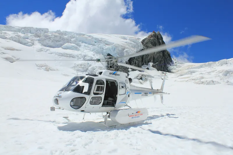 Helikopter bei einer Schneelandung unter einem Gletscherabbruch in den Southern Alps