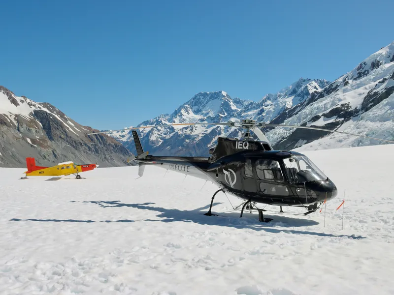Helikopter und Skiplanes auf einem Schneefeld vor Aoraki/Mount Cook